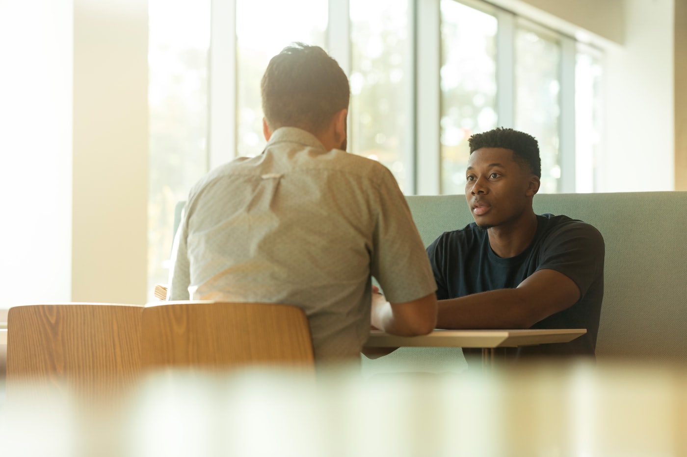 Two professionals in a focused discussion in a sunlit space — commercial real estate advisory
