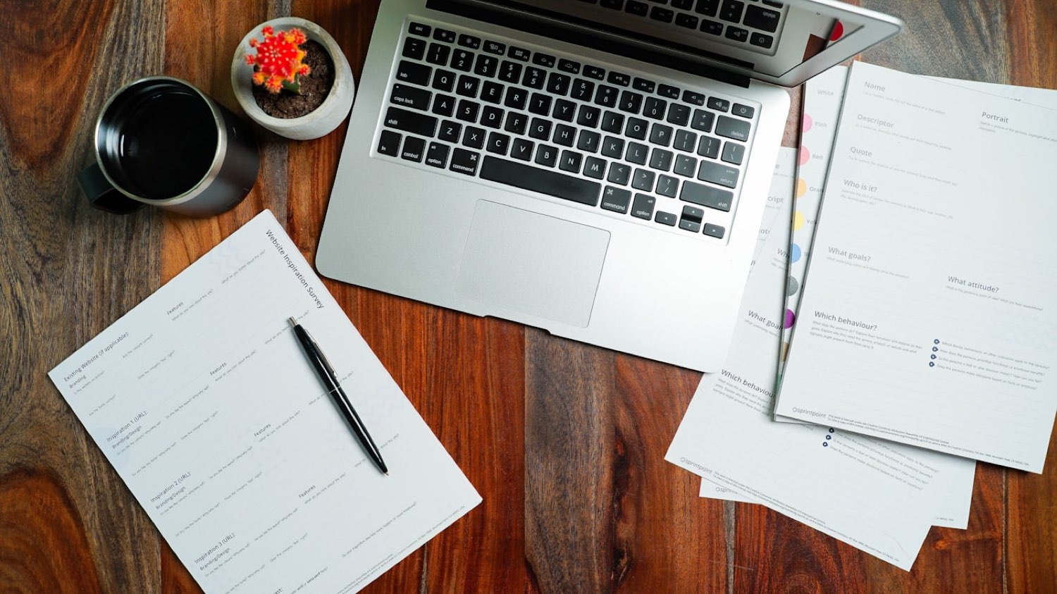 Property documents, a pen and a laptop on a warm wooden desk — investment advisory review